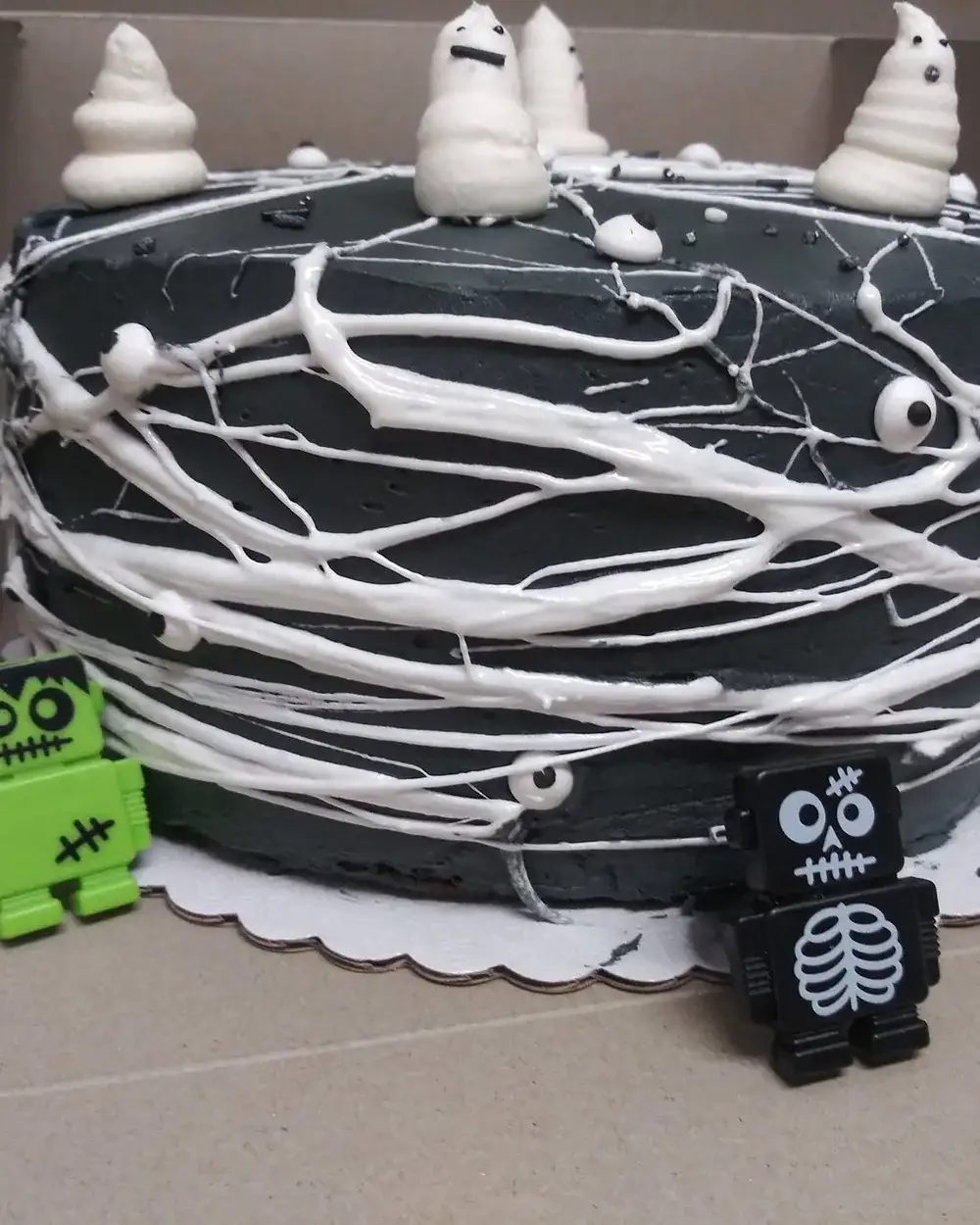 A Halloween cake piped with a cobweb pattern and topped with meringue ghosts